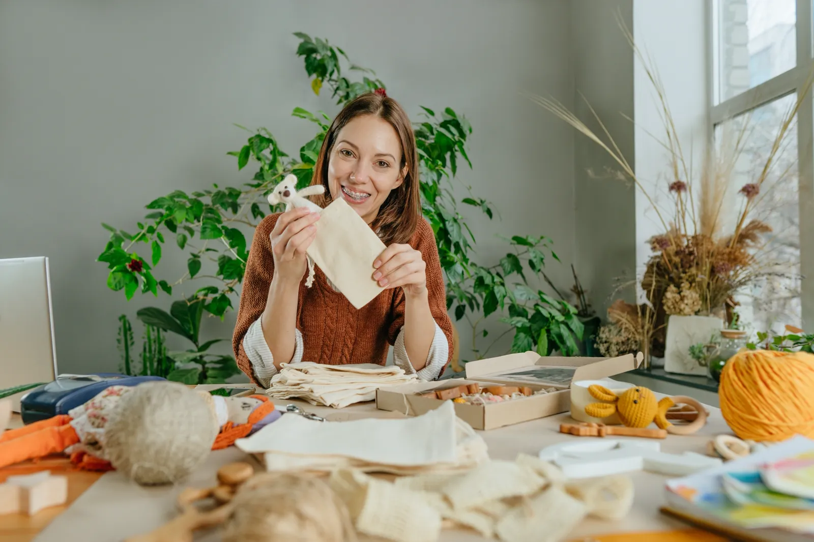 A woman holding a finished sewing project with a stuffed animal, content and quiet