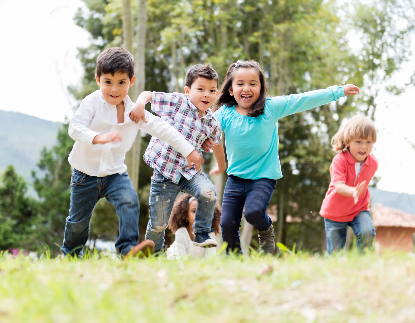 A happy group of children playing together at a park outdoors, no screens visible