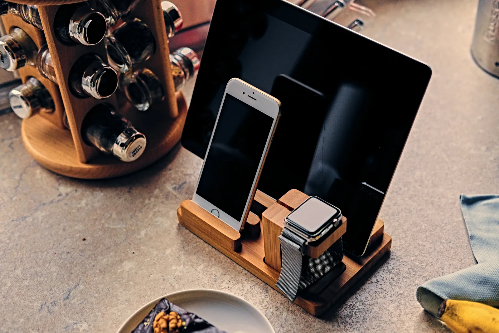 A bamboo wooden charging stand holding a smartwatch, tablet, and smartphone in a shared family space