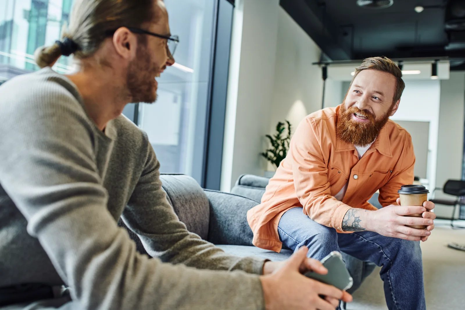 Two men chatting in a relaxed way in a modern office, an easy adult conversation between friends or colleagues