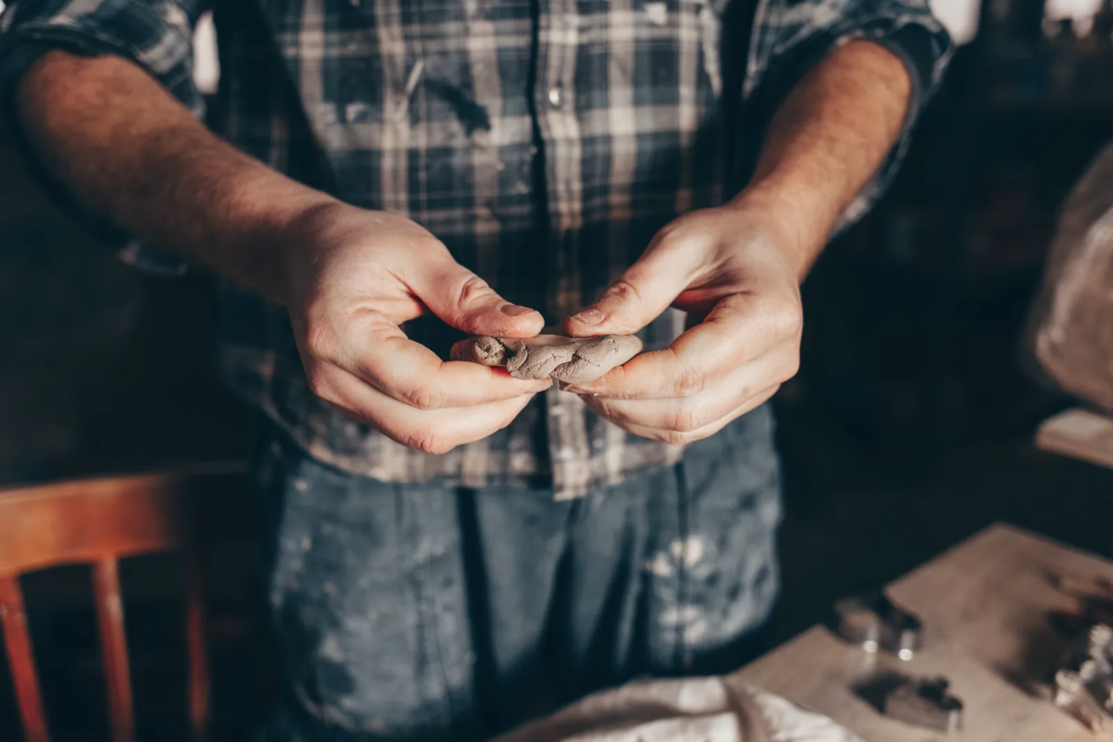 A craftsman shaping clay in a rustic workplace, hands on the wheel, focused work