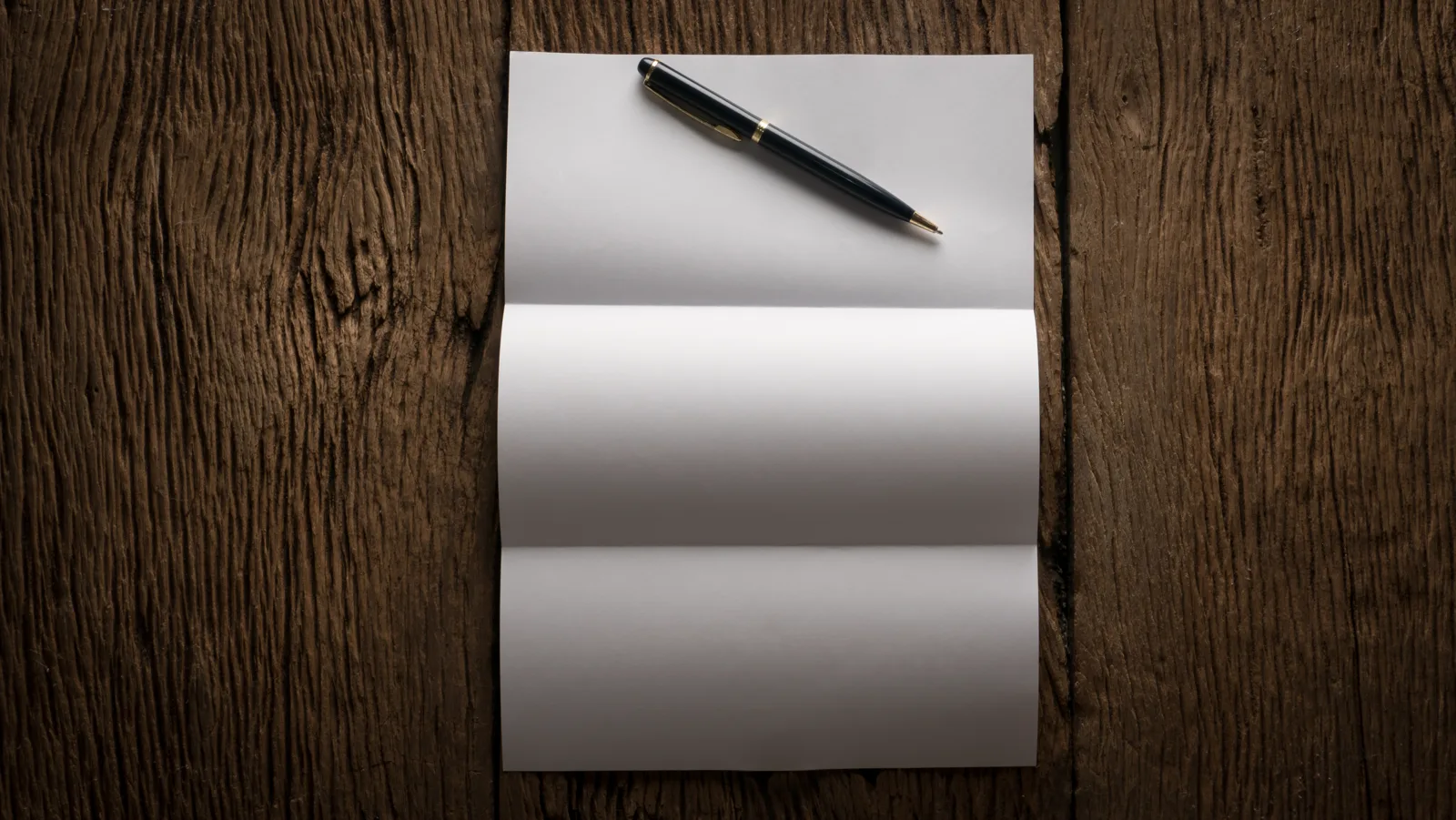 A blank sheet of paper and a fountain pen resting on a wooden table, soft natural light