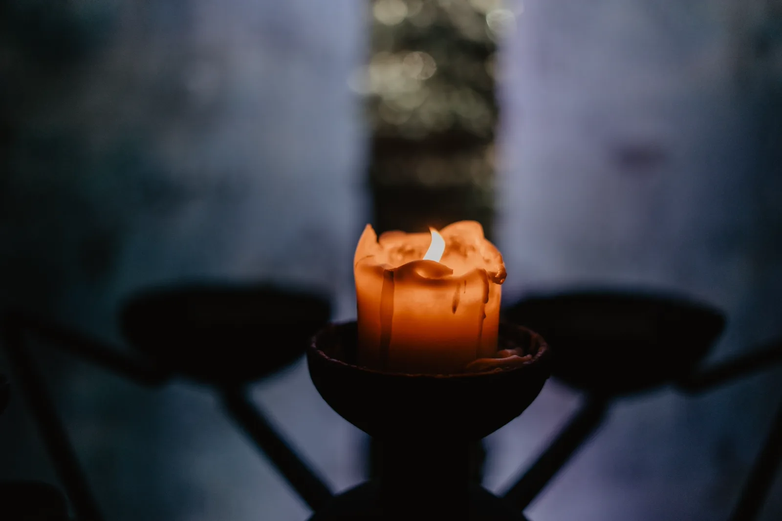 A single candle glowing softly in a quiet dark interior, intimate stillness