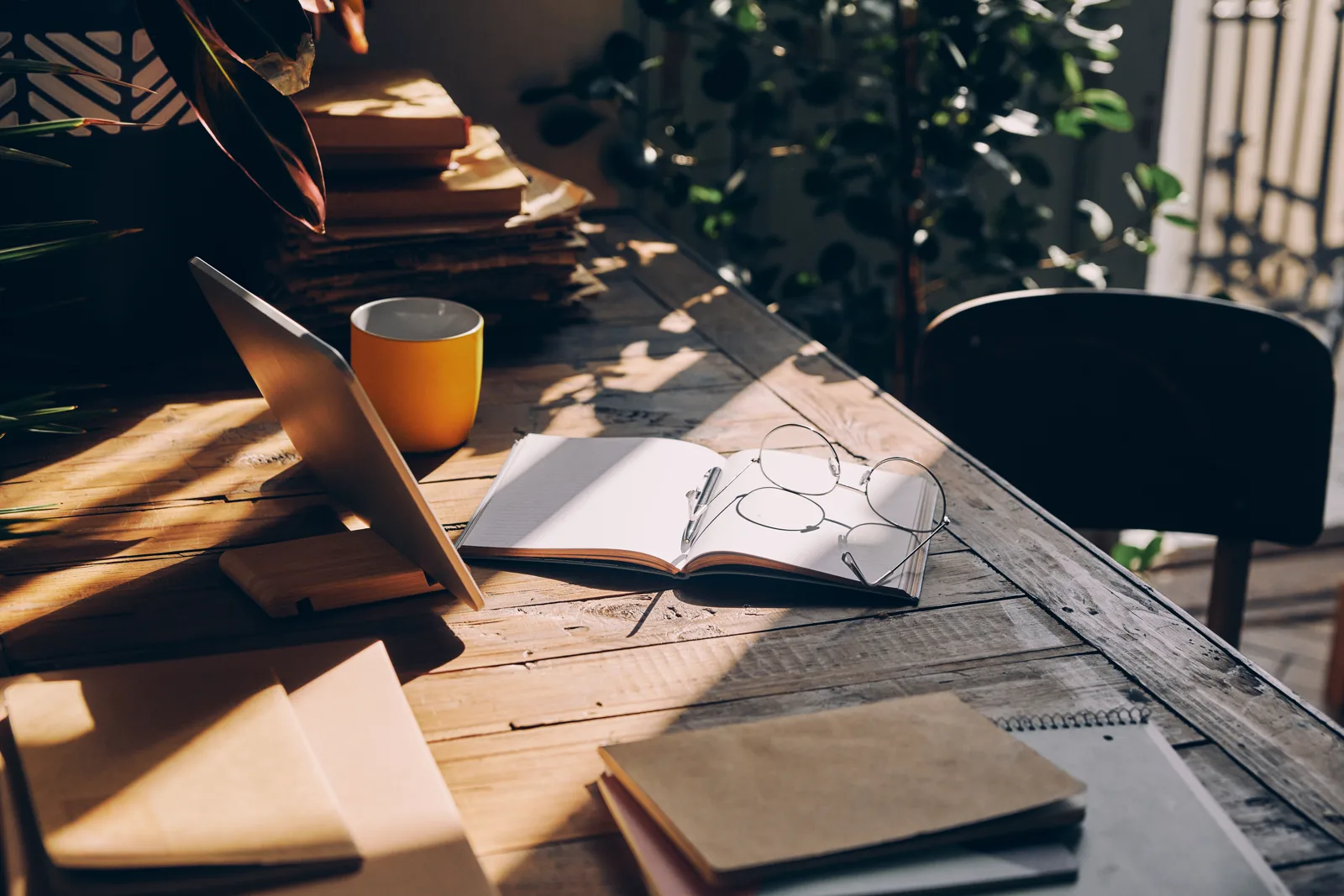 A close-up of a workspace with warm sunlight falling across the desk, hopeful and grounded