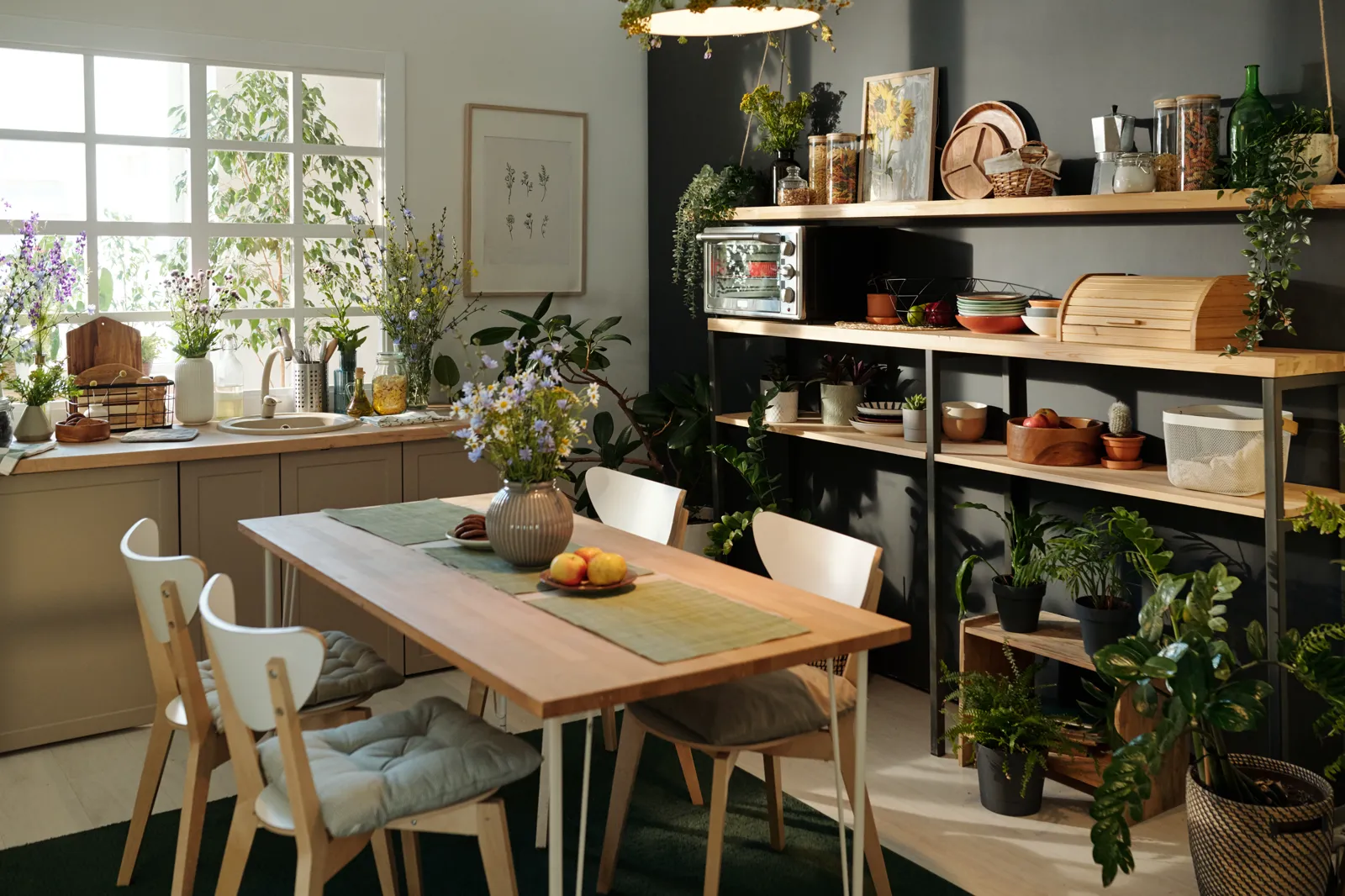 A bright dining area filled with houseplants and natural light, books on the table