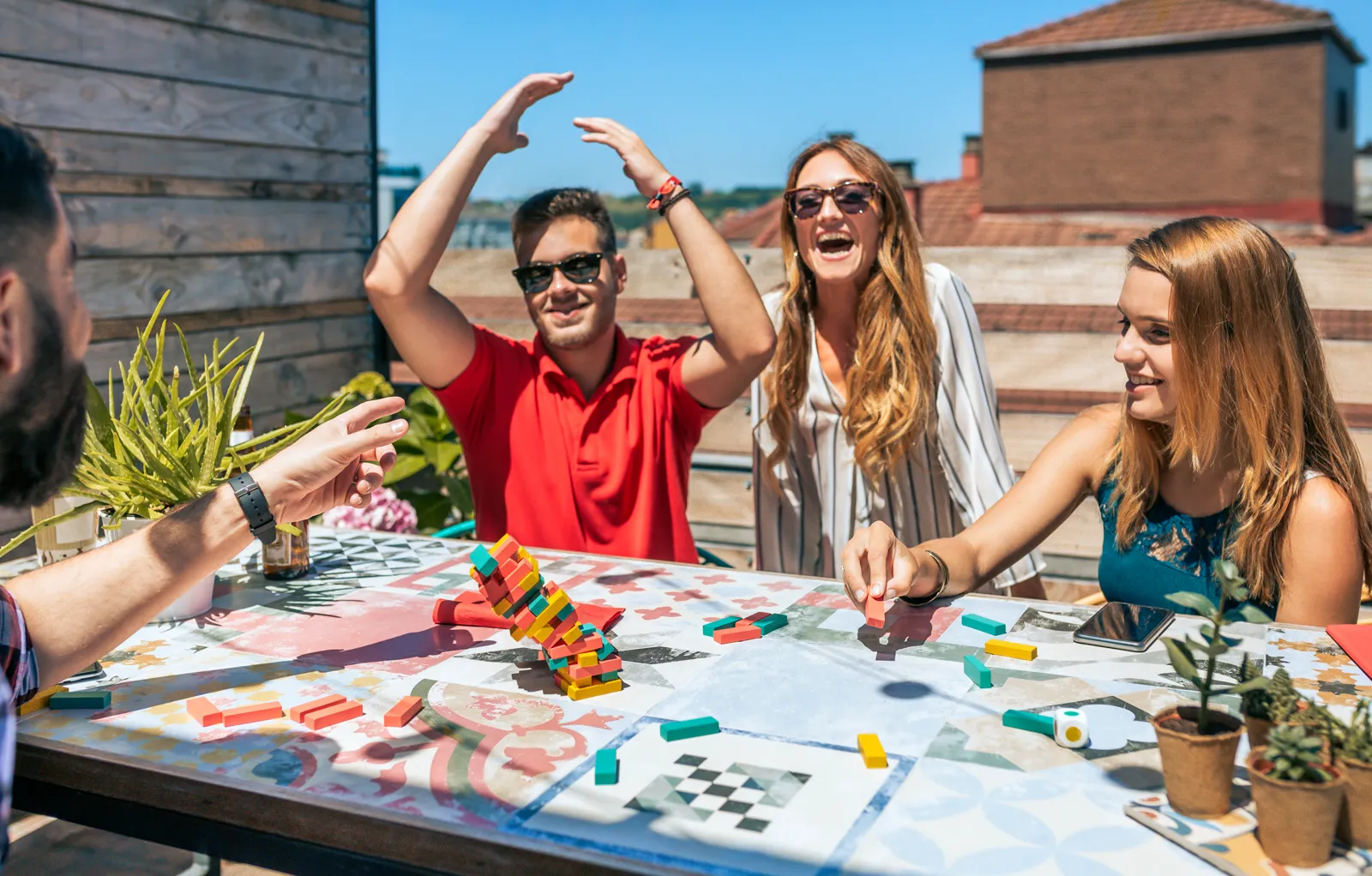 Friends playing a board game on a rooftop at golden hour, laughing