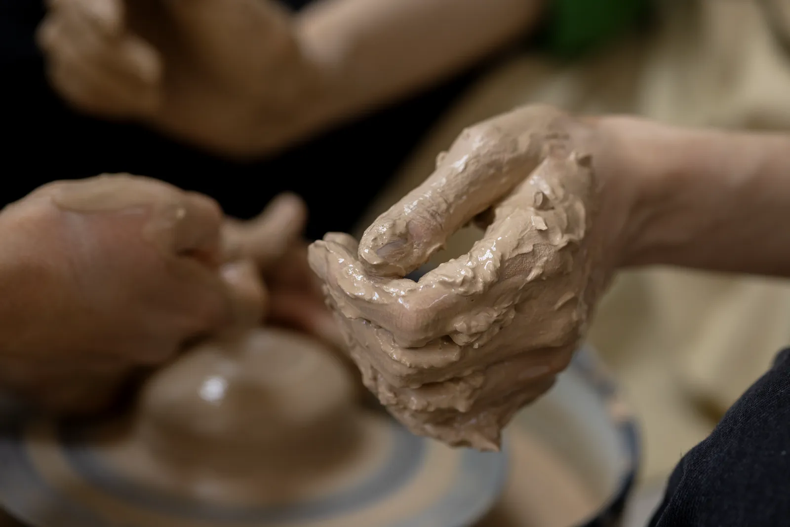 Close-up of a woman's hand shaping wet clay on a pottery wheel