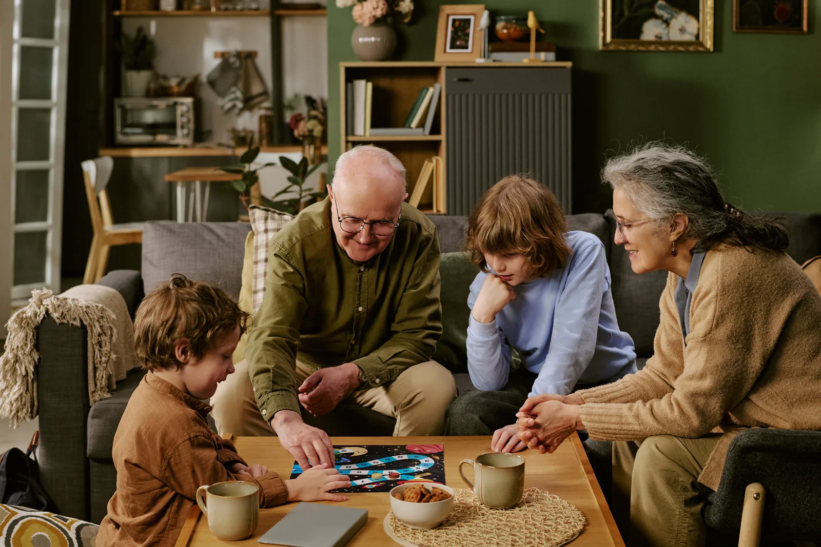 A family playing a board game together at a table, laughing, warm light
