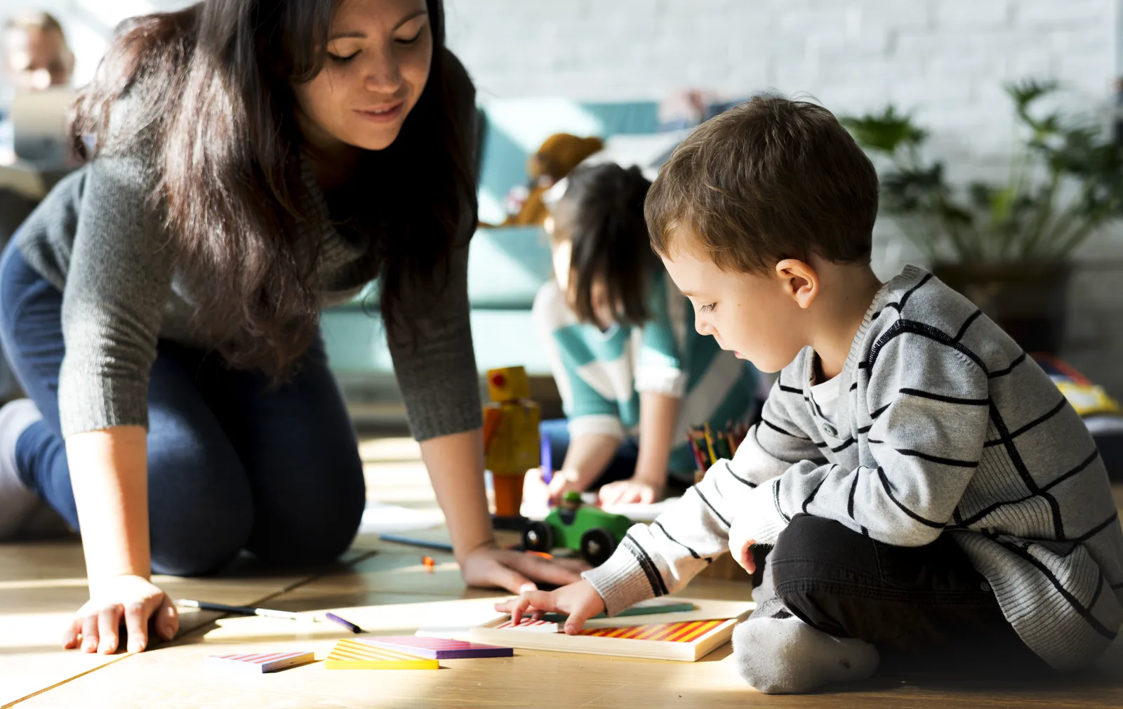 A parent down at a child's eye level, both fully engaged, warm window light