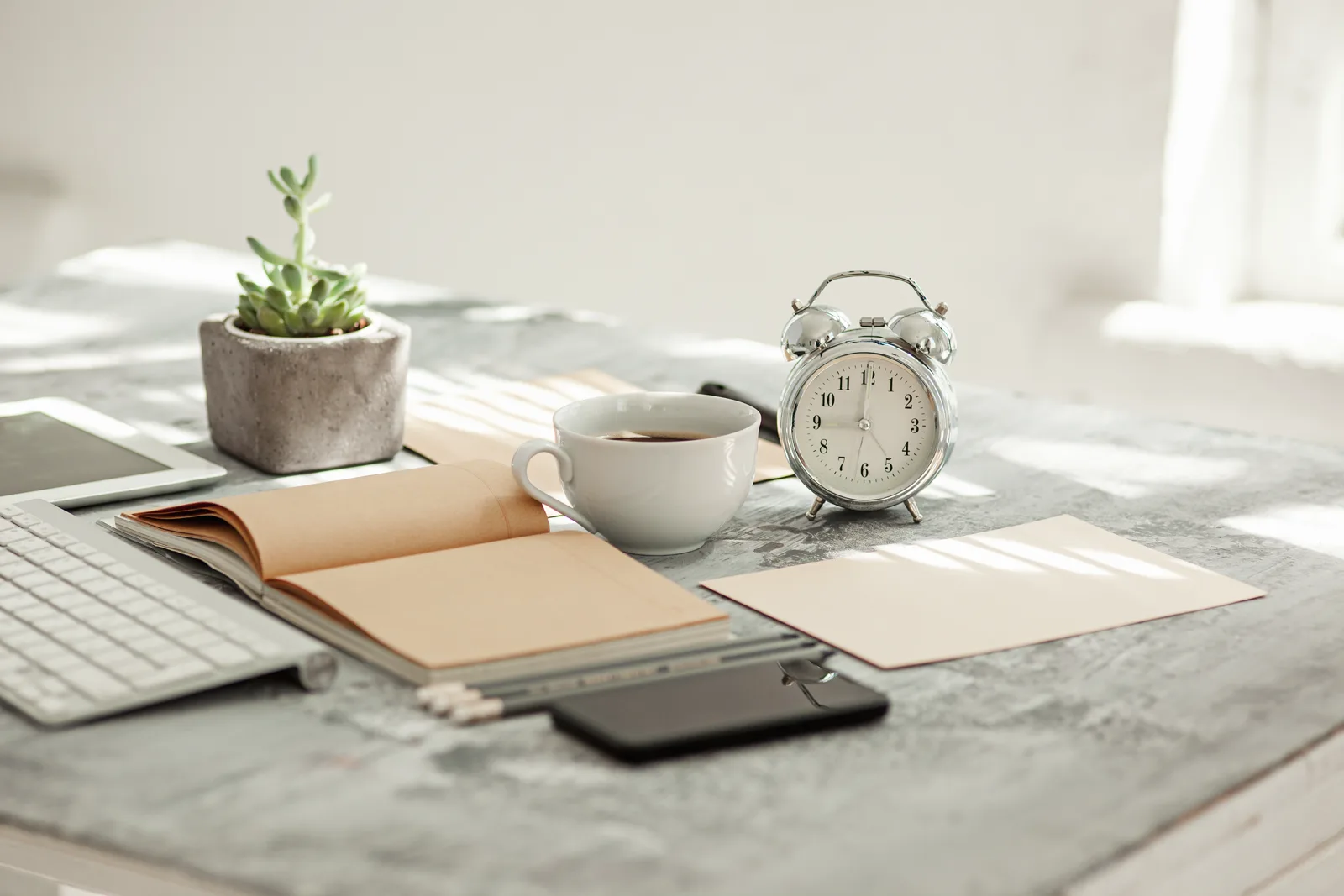 A tidy desk with a notebook, a timer, and a planner in warm natural light