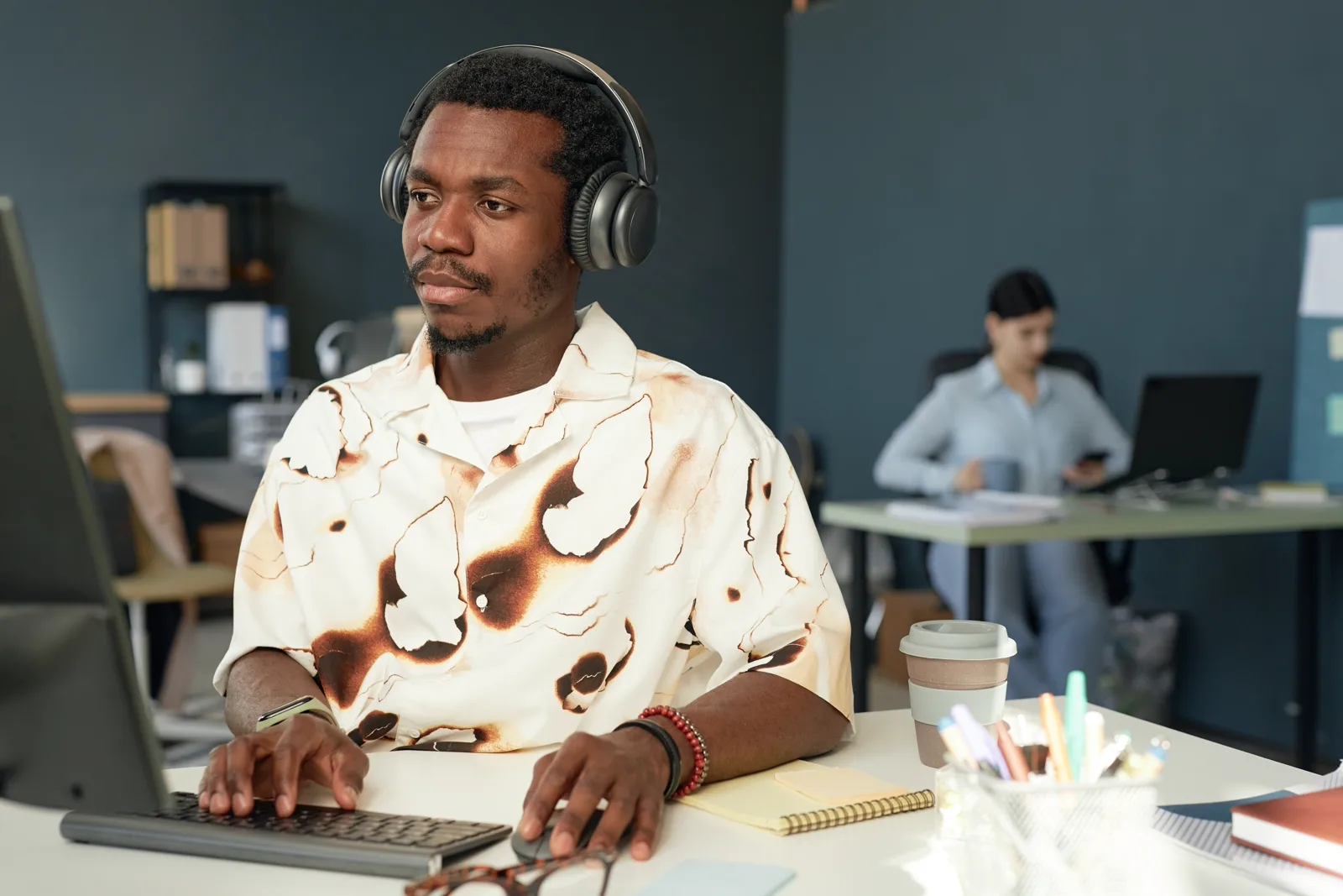 A focused person working at a clean desk with headphones in soft office light