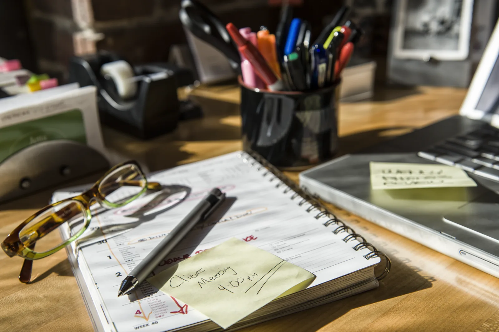 A tidy desk with files, folders and a notebook in warm light
