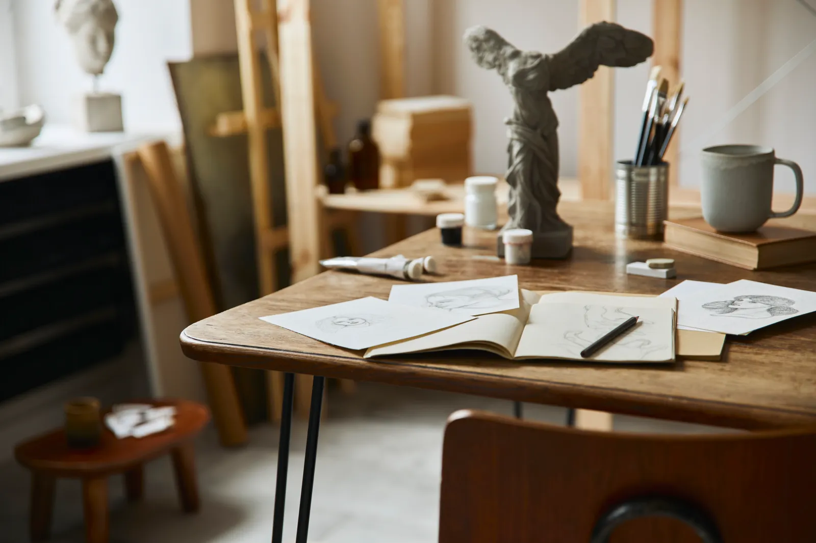 A sunny art studio with sculptures and sketches scattered around, a working space
