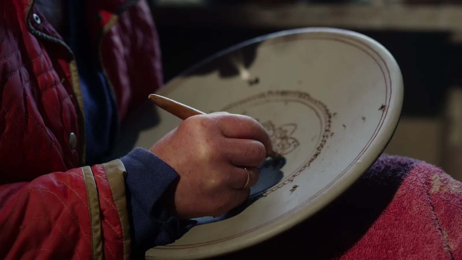 An artist working with a wooden tool on a piece in progress