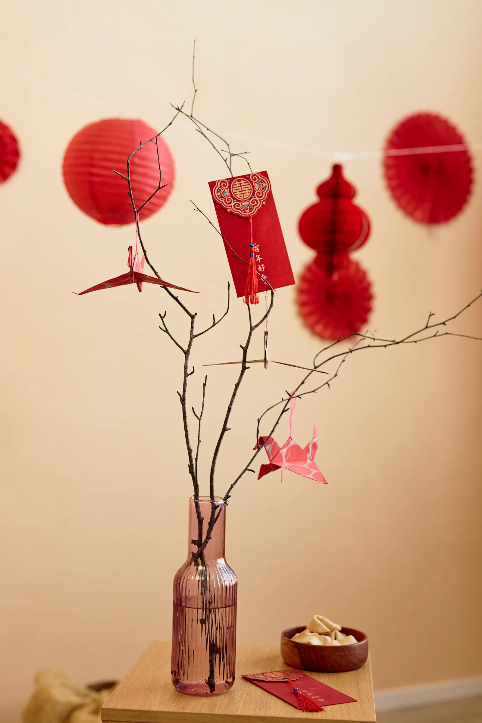 A bare branch standing in a vase, hung with folded paper notes, soft light