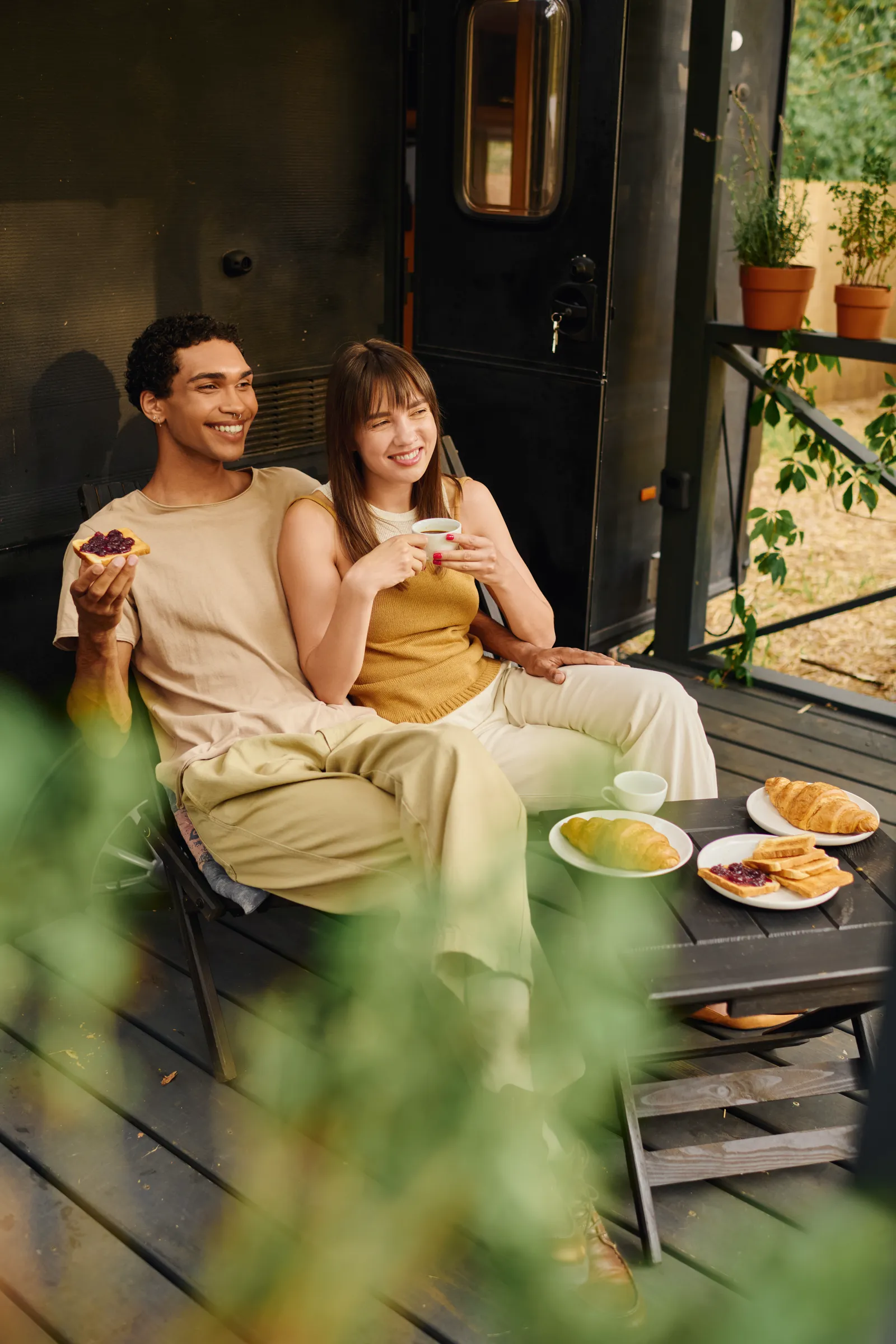 A cheerful couple enjoying breakfast outdoors near mountains, slow morning energy