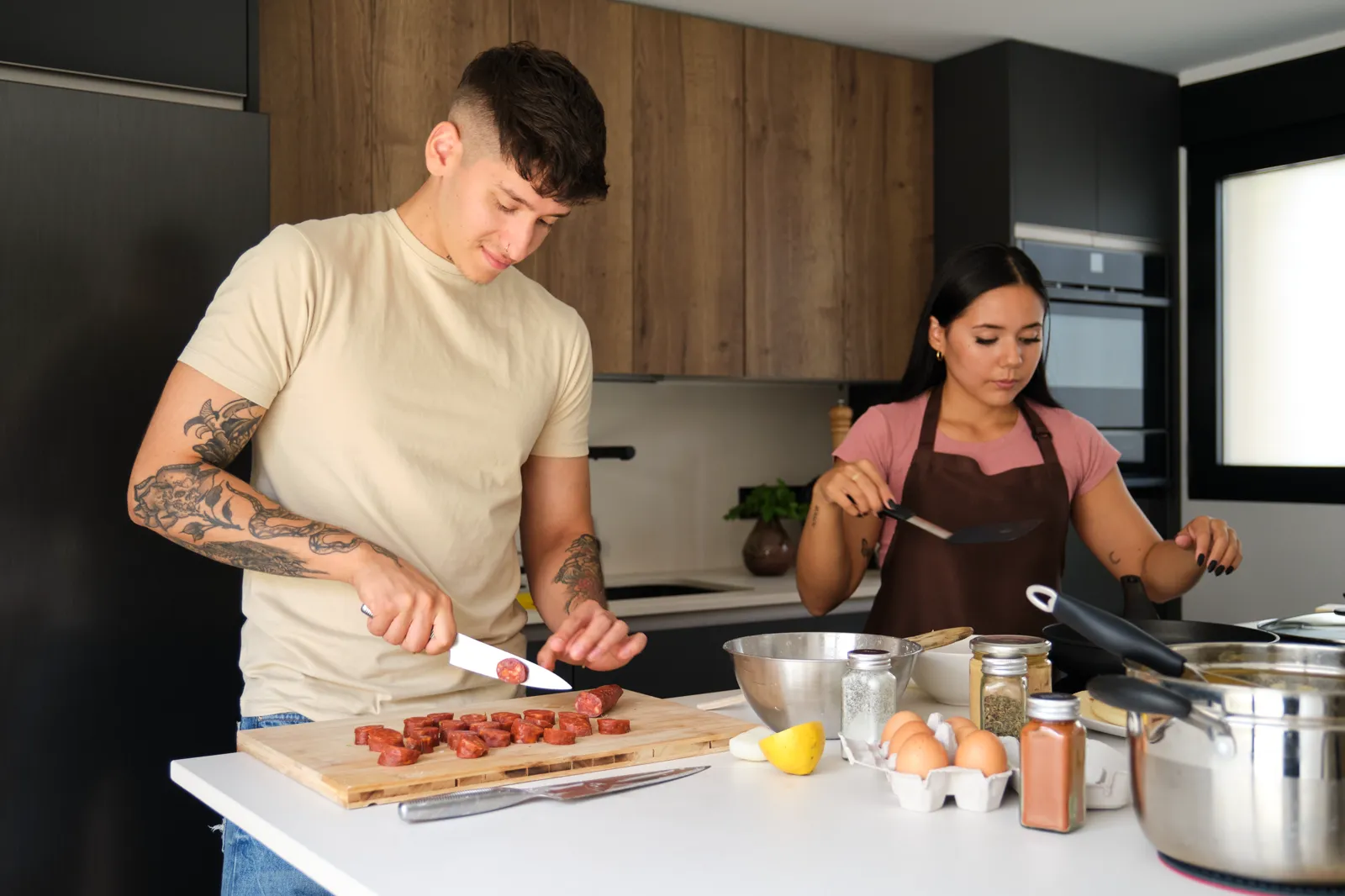 Two young adults preparing food together in a kitchen, focused and at ease
