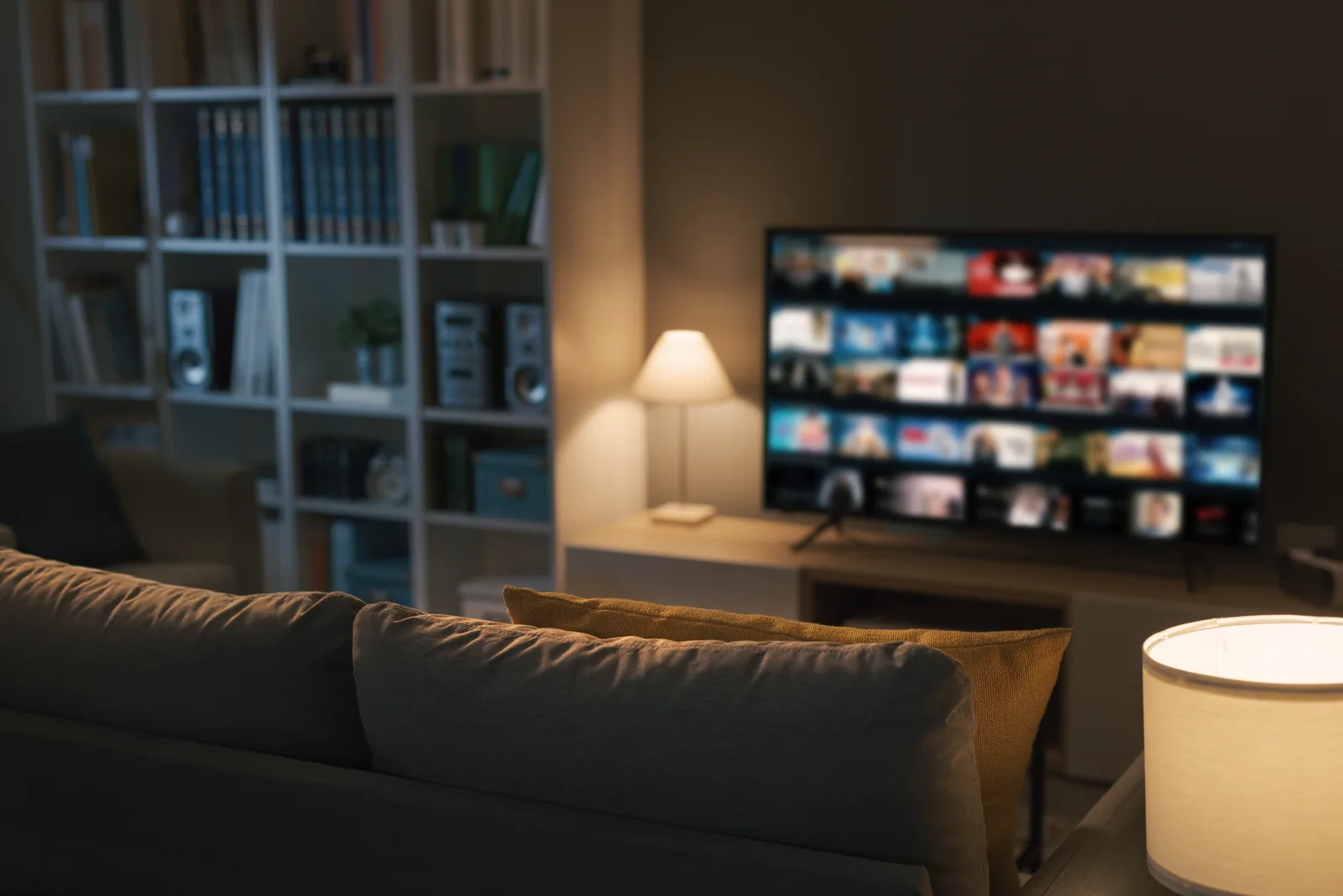 A comfortable couch facing a wall-mounted TV in a softly lit living room, evening light